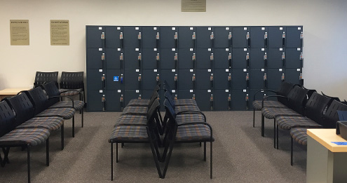 Waiting room with chairs in front of storage lockers near the check-in station.