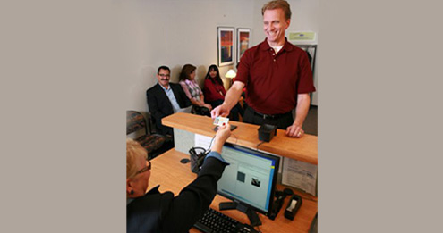 Test center administrator matching the driver license ID of testing candidate to candidate profile on computer screen.
