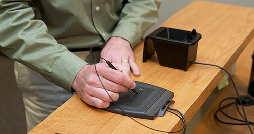 Testing candidate signing his name to digital signature pad at the front desk.