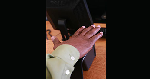 Testing candidate placing palm of his hand on top of palm vein reader at the front desk.